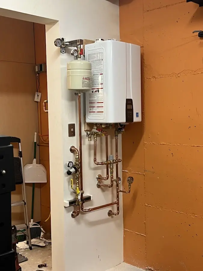 Plumbing technician inspecting water heater connections in Tomahawk